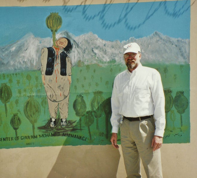Рон Макмаллен позирует рядом с фреской, посвященной борьбе с маком в Кабуле, Афганистан.