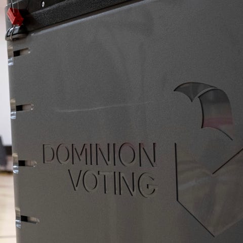 A worker passes a Dominion Voting ballot scanner w