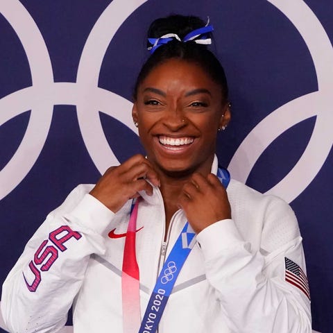 Simone Biles poses with her bronze medal after the