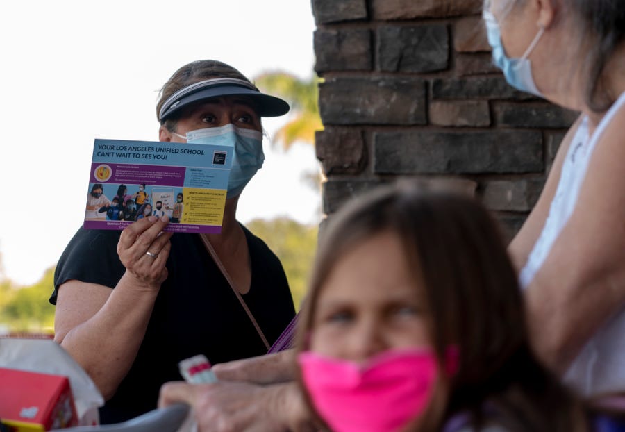 Hilda Martinez, a community organizer with the L.A. Education Recovery Fund hands out informational flyers about the Los Angeles Unified School District's requirements for students to return to in-person classes outside a Target store in Pacoima, Calif., Aug. 10, 2021.