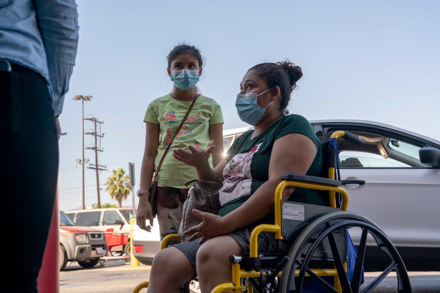 Edia Cordero and her daughter Jasmin Cordero, 11, talk with workers with the L.A. Education Recovery Fund outside a Target store in Pacoima, , Calif., Aug. 10, 2021. Cordero, who is unvaccinated, says that she would get her daughter vaccinated if Los Angeles Unified School District if the district requires proof of the students vaccination, 