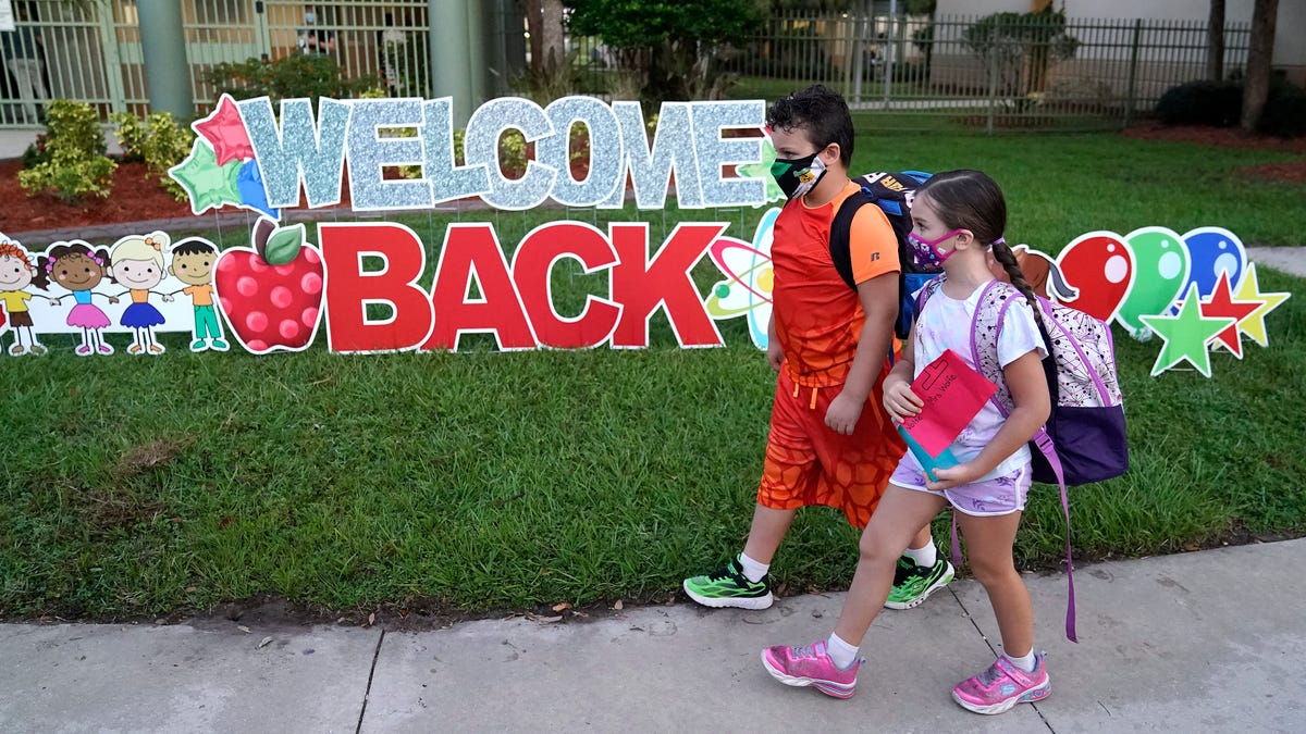 Students wearing protective masks walk past a "Welcome Back" sign before the first day of school at Sessums Elementary School Tuesday, Aug. 10, 2021, in Riverview, Fla.