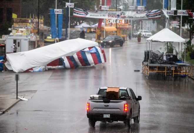 A truck carries the podium that would have been used for the ribbon cutting ceremony for the Illinois State Fair down Main Street as a storm hits the Illinois State Fairgrounds on Thursday. [Justin L. Fowler/The State Journal-Register]