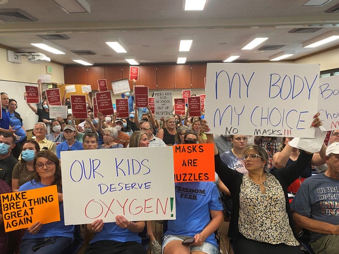 Members of the audience at the TSC board meeting on Aug. 11, 2021 hold signs with messages both for and against a mask mandate.