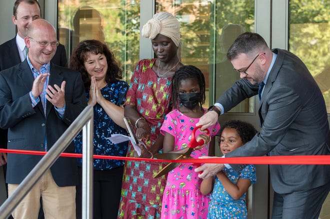 Worcester Public Library Executive Director Jason Homer, right, cuts the ribbon on the new entrance of the library with assistance from Aavin Hill, 5, in blue, and Bineta Diallo, 8, in pink, on Thursday.