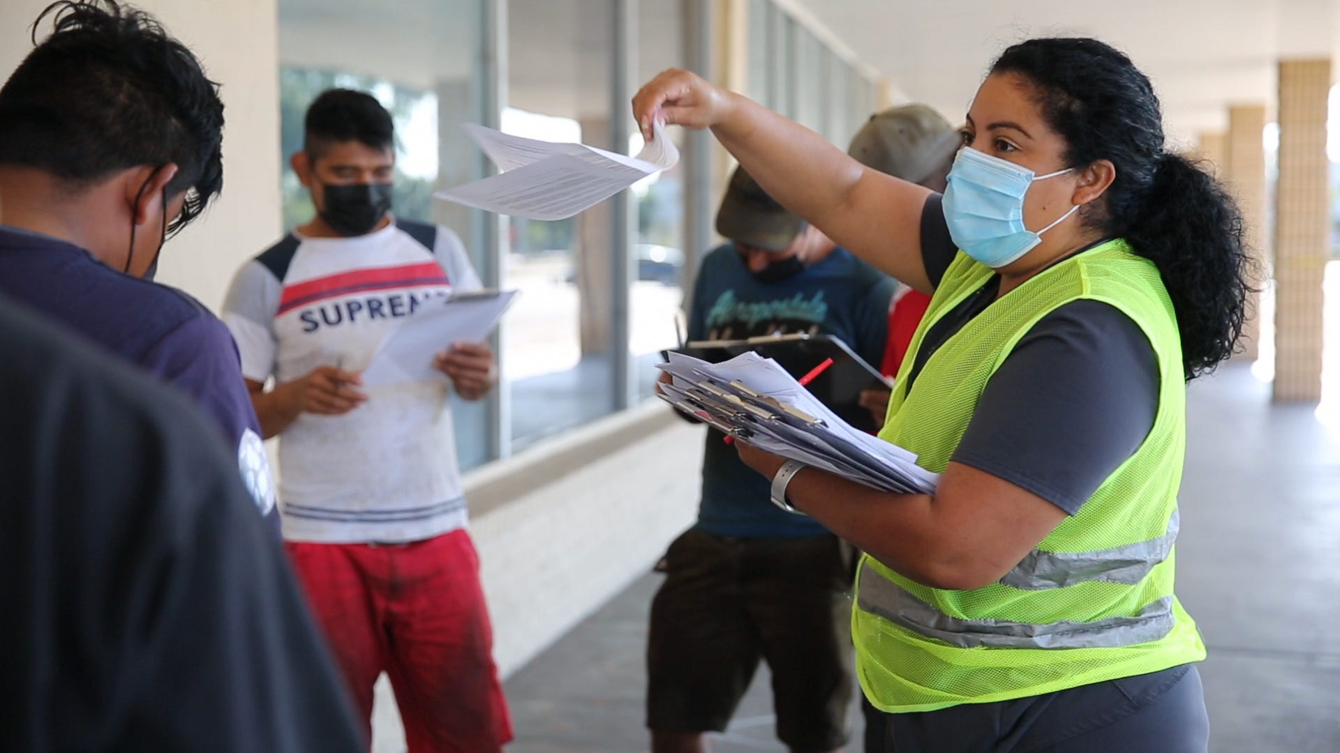 Midania Hinojosa helps a group of farmworkers with their paperwork while they wait in line during a vaccine clinic for farmworkers at the Florida Department of Health in Collier County site on Lake Trafford Road in Immokalee on Saturday, April 10, 2021.