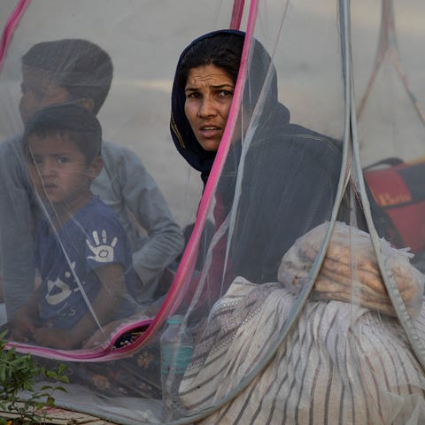 Displaced Afghans sit in a tent at a makeshift IDP