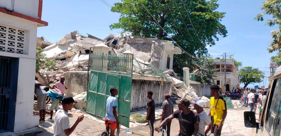 People stand outside the residence of the Catholic bishop after it was damaged by an earthquake in Les Cayes, Haiti, Saturday, Aug. 14, 2021.