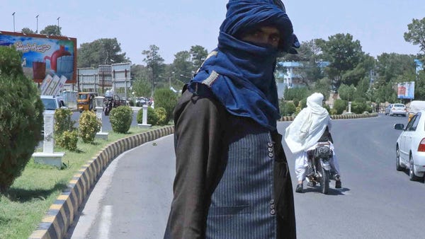 A Taliban fighter stands guard on a street in Hera