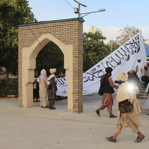 Taliban fighters raise their flag at the Ghazni pr