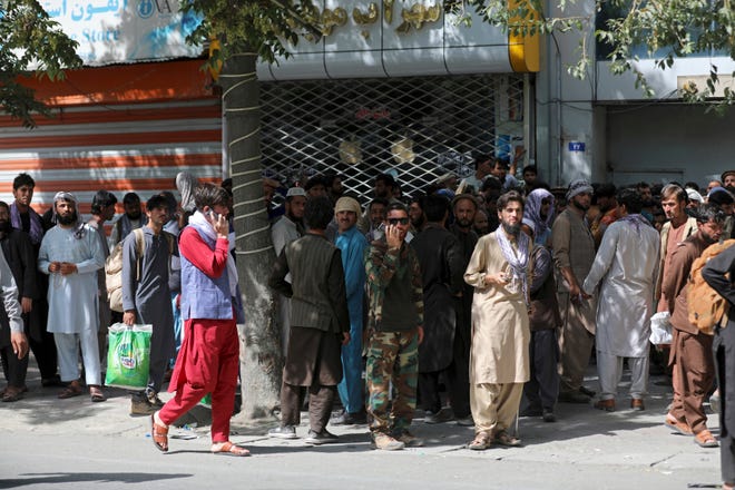 Afghans wait in line for hours to withdraw money in front of Kabul Bank in Afghanistan on Aug. 15. Taliban fighters entered Kabul, seeking the unconditional surrender of the central government.