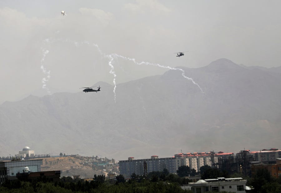 Anti-missile decoy flares are deployed as U.S. Black Hawk military helicopters and a dirigible balloon fly over the city of Kabul, Afghanistan, Sunday, Aug. 15, 2021. Taliban fighters entered the outskirts of the Afghan capital on Sunday and said they were awaiting a 