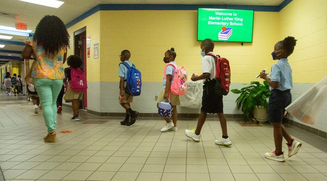 Second grade teacher Lakeisha Robinson walks her students to their classroom on the first day at Martin Luther King Jr. Elementary School on Aug. 16, 2021. 