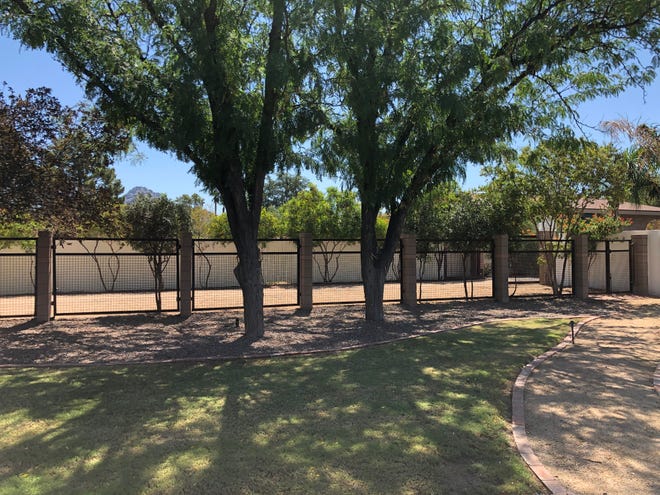 Mature trees give some privacy and a lot of shade alongside the fence that straddles the yard and private road that leads to this home.