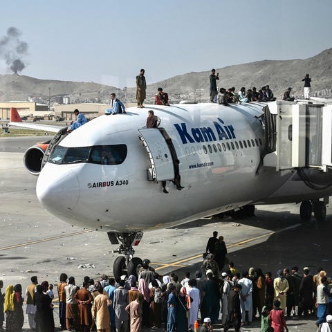 Afghan people climb atop a plane at the Kabul airp