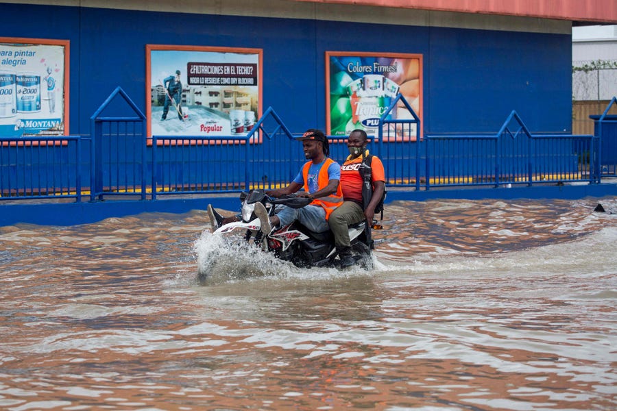 A man rides on a motorcycle through a flooded street after the passage of the Tropical Storm Grace in Santo Domingo, on August 16, 2021. - The US National Hurricane Center (NHC) warned that it is possible that flash floods and landslides may occur today in the Dominican Republic and Haiti due to Grace, which at 8.00 hours (12.00 GMT) was 125 miles (200 kilometers) east of the Haitian capital, Port-au-Prince.