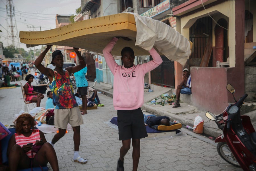 Men carry a mattress as people sleep on the streets after Saturday´s  7.2 magnitude earthquake in Les Cayes, Haiti, Sunday, Aug. 15, 2021.