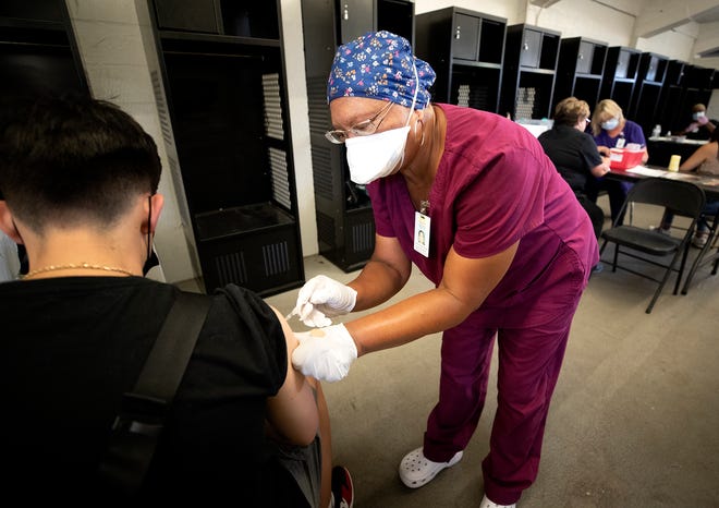 RN Herma Robotham administers a Covid-19 vaccine to Thomas Ceciliano during a Polk County Health Department hold pop-up vaccine clinic held in the Vistor locker room at Bryant Stadium in Lakeland Fl. Tuesday August 17 2021.  ERNST PETERS/ THE LEDGER