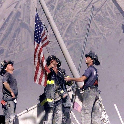 Firefighters raise a flag at Ground Zero following