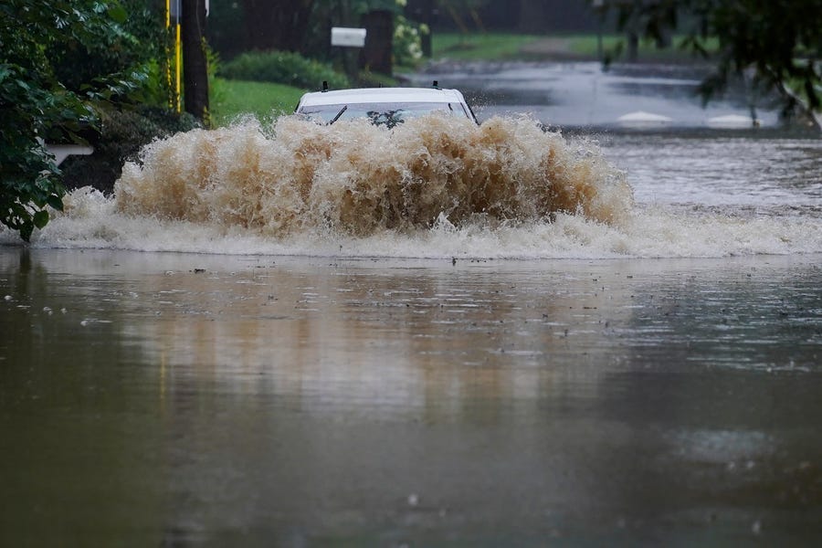A car attempts to drive through flood waters near Peachtree Creek near Atlanta, as Tropical Storm Fred makes its way through north and central Georgia on Tuesday, Aug. 17, 2021.