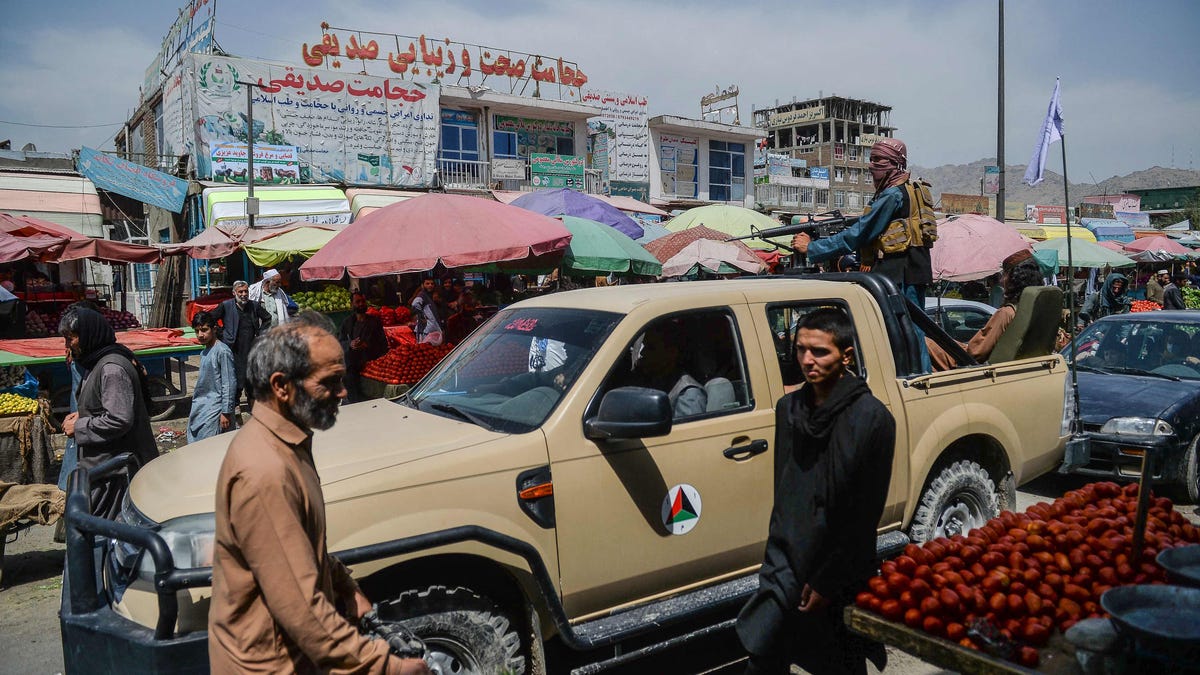 Taliban fighters on a pickup truck move around a market area, flocked with local Afghan people at the Kote Sangi area of Kabul on Aug. 17, 2021, after Taliban seized control of the capital following the collapse of the Afghan government.