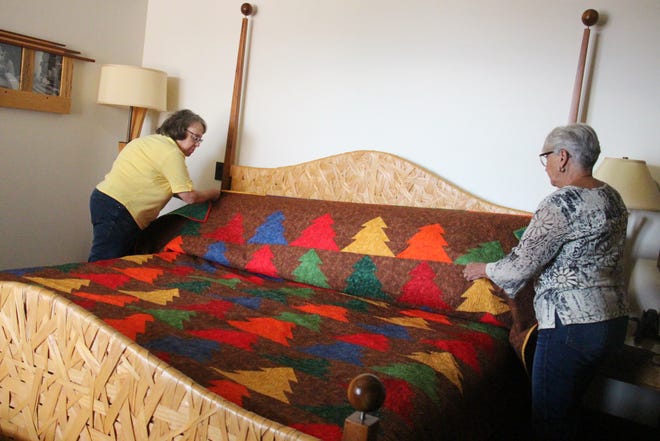 Members of the Perry Piecemakers Quilt Guild lay out a quilt they created for the Woodworking Room at the Hotel Pattee on Wednesday, Aug. 18.