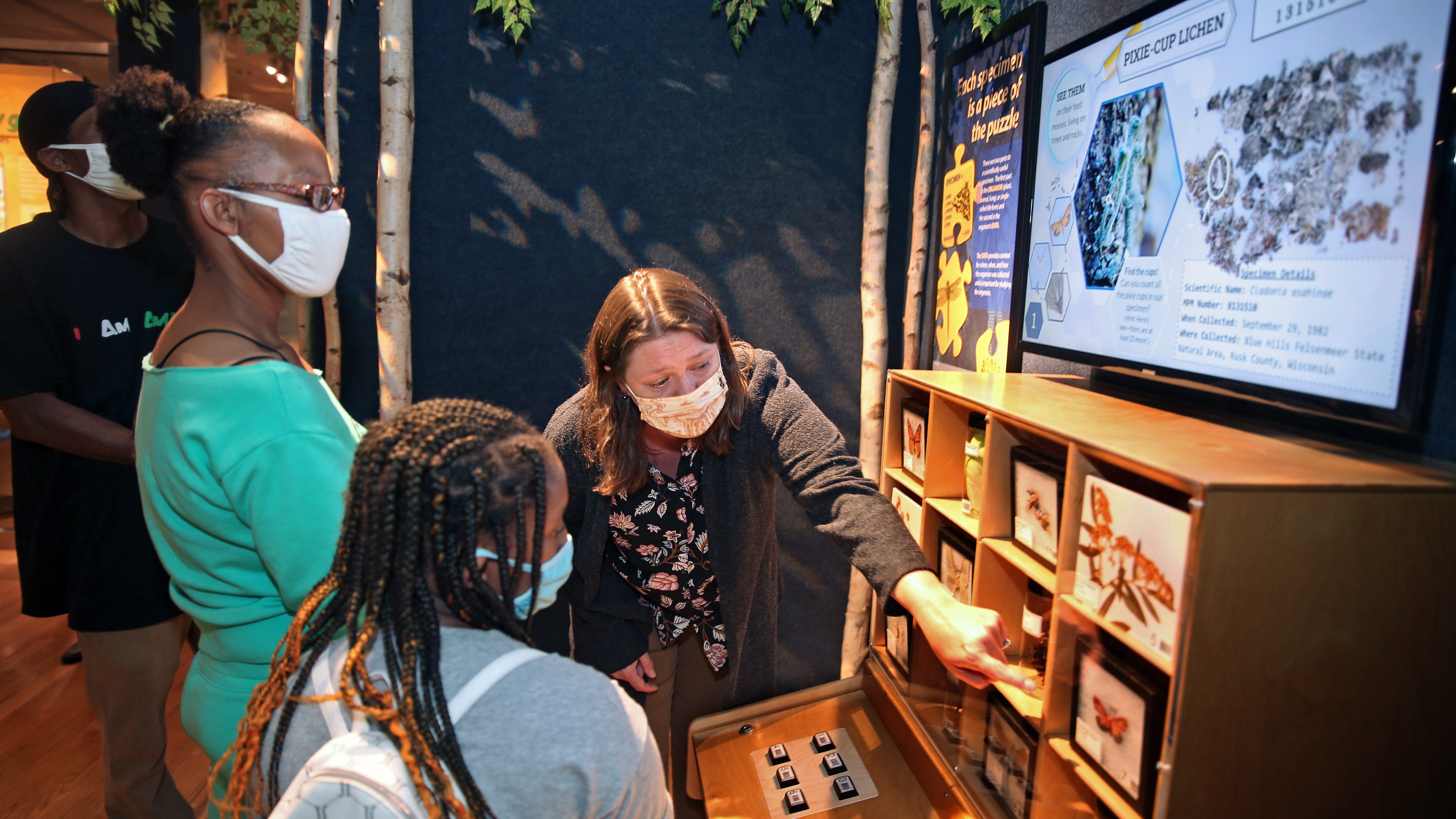 Jennifer Zaspel (right) of the Milwaukee Public Museum talks about bugs to Angel Quinn, center, and her daughter Aaliyah Baldwin, 12, left, during a sneak preview of the museum's Puelicher Butterfly Wing.