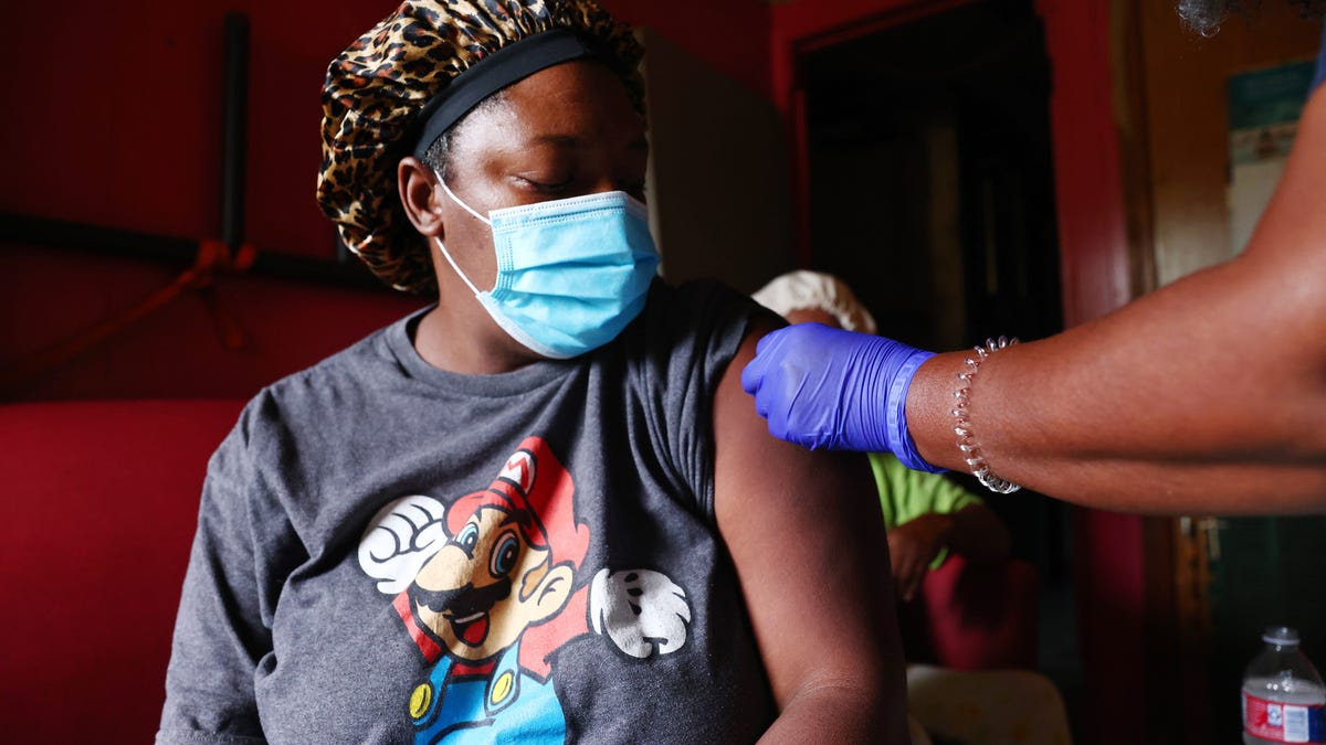 Nurse Carla Brown (R) applies an adhesive bandage after vaccinating two residents in their home on August 17, 2021 in Baton Rouge, Louisiana. Brown embarked on a personal mission to save lives and vaccinate members of underserved communities in Baton Rouge after her husband David died of COVID-19.