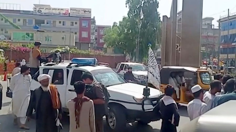 Taliban fighters gather around a vehicle during a protest in Jalalabad, Afghanistan on Wednesday, Aug. 18, 2021.  Taliban militants have attacked protesters in eastern Afghanistan who dared to take down their banner and replace it with the country's flag. At least one person was killed in the attack that fueled fears about how the insurgents would govern this fractious nation.