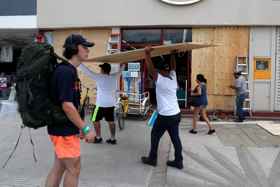 Workers cover shop windows with plywood in Tulum, Quintana Roo State, Mexico, Wednesday, Aug. 18, 2021. 