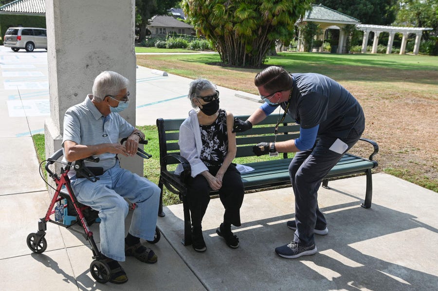 Registered nurse Kevin Grellman prepares to give a third "booster" dose of Pfizer Covid-19 vaccine to Jose Gomez, 80, (L) and his wife Armida Gomez, 81, during a vaccination clinic hosted by Tournament of Roses and the Pasadena Department of Public Health on August 19, 2021 at Tournament House in Pasadena, California.