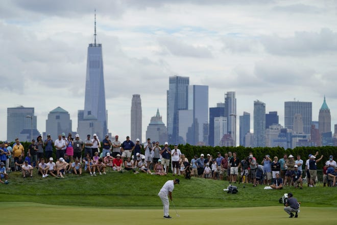 Jon Rahm putts on the 18th green at Liberty National on Friday, with the Manhattan skyline in the background. The final round of The Northern Trust has been postponed to Monday because of the forecasted effects of Hurricane Henri.