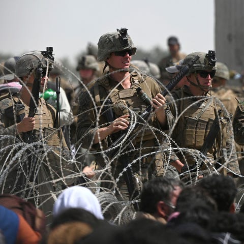U.S. soldiers stand guard behind barbed wire as Af