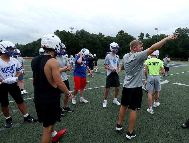 Norwell High head coach Mark Killinger points to a corner of the field while splitting up the team for conditioning exercises during football practice at Norwell High on Friday, Aug.  20, 2021.