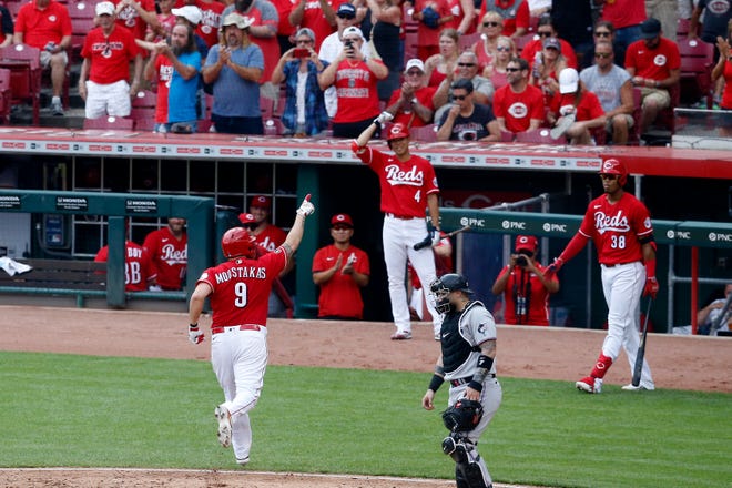 Cincinnati Reds third baseman Mike Moustakas (9) celebrates as he crosses the plate as the go-ahead run on a solo home run in the fifth inning of the MLB National League game between the Cincinnati Reds and the Miami Marlins at Great American Ball Park in downtown Cincinnati on Sunday, Aug. 22, 2021. The game was tied 1-1 in the top of the fifth.
