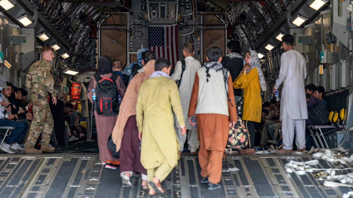 A U.S. Air Force loadmaster, assigned to the 816th Expeditionary Airlift Squadron, assists evacuees aboard a C-17 Globemaster III aircraft in support of Operation Allies Refuge at Hamid Karzai International Airport, Kabul, Afghanistan, on Aug. 20.