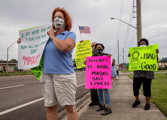 People hold signs supporting mask mandates outside the Lake County School District office in Tavares on Aug. 23.