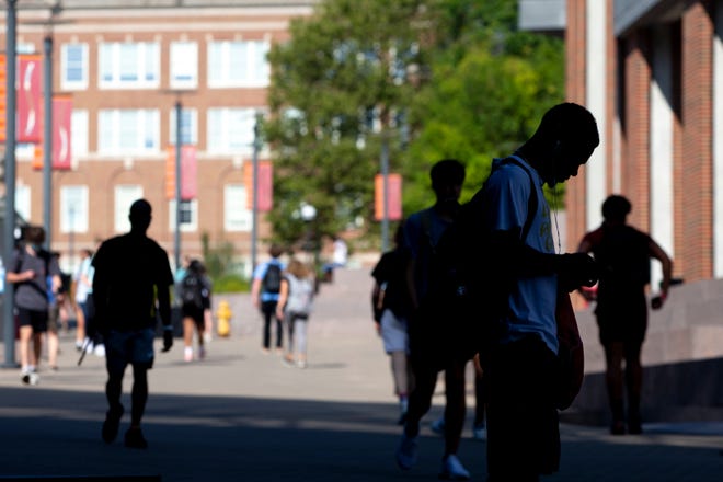 A student looks at his phone on the campus of the University of Cincinnati on Monday, Aug. 23, 2021.