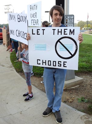 Christopher Brown, with three children in Coshocton City Schools, stands in front of the main entrance Monday morning with a sign protesting a mask requirement voted on by the board of education on Thursday. Brown started a petition on chagne.org to reverse the decision that had more than 1,500 signatures Monday morning. About 25 people participated in the peaceful protest.