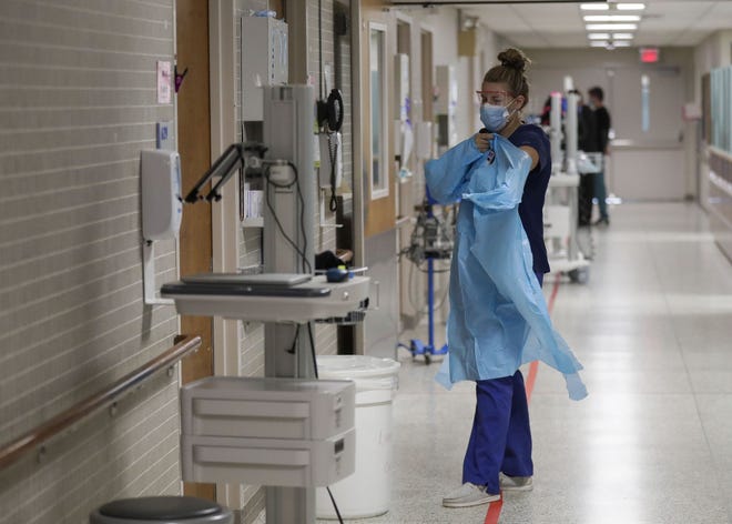 A nurse puts on a protective gown before entering a patient's room on the sixth floor COVID-19 wing Aug. 19 at Marshfield Medical Center in Marshfield. The hospital is not accepting transfers from out-of-network facilities as a surge in COVID-19 cases left only two ICU beds available out of 125 in northcentral Wisconsin.
