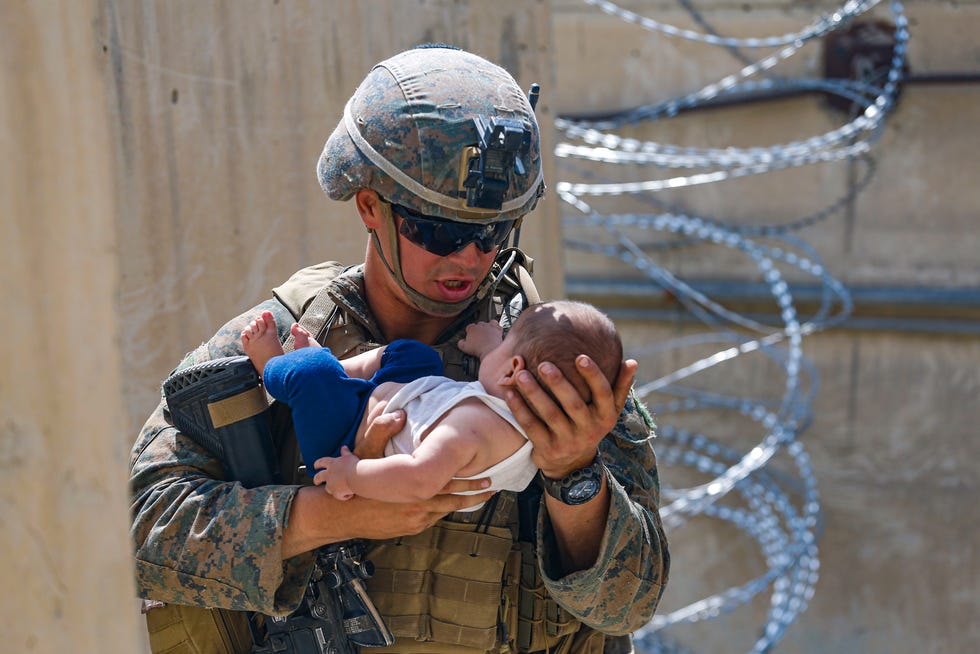 A U.S. Marine assigned to 24th Marine Expeditionary Unit comforts an infant while they wait for the mother during an evacuation at Hamid Karzai International Airport in Kabul, Afghanistan, on Aug. 21, 2021.