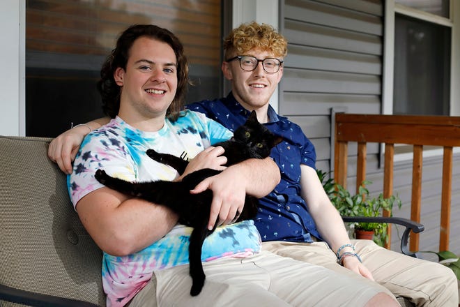 Philip Baltzer, left, holds Raja the cat, while sitting next to boyfriend Nick Mayes on the porch of their South Side home. Baltzer, 24, says he is finally happy with who he is and his life, despite going through painful conversion therapy with a local pastor a few years ago.