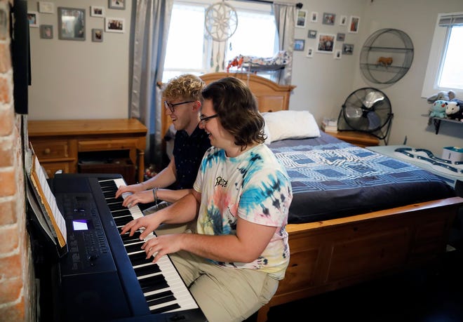 Philip Baltzer, in the forefront, and his boyfriend Nick Mayes play the piano in the bedroom of their South Side home. Both Baltzer and Mayes are music teachers. Baltzer, 24, said he recently realized he'd been through conversion therapy by a local pastor after watching the Netflix documentary "Pray Away."