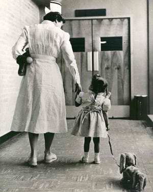 Oklahoma Medical Research Hospital Head Nurse Marian MacAuley walks with a young patient in 1955.