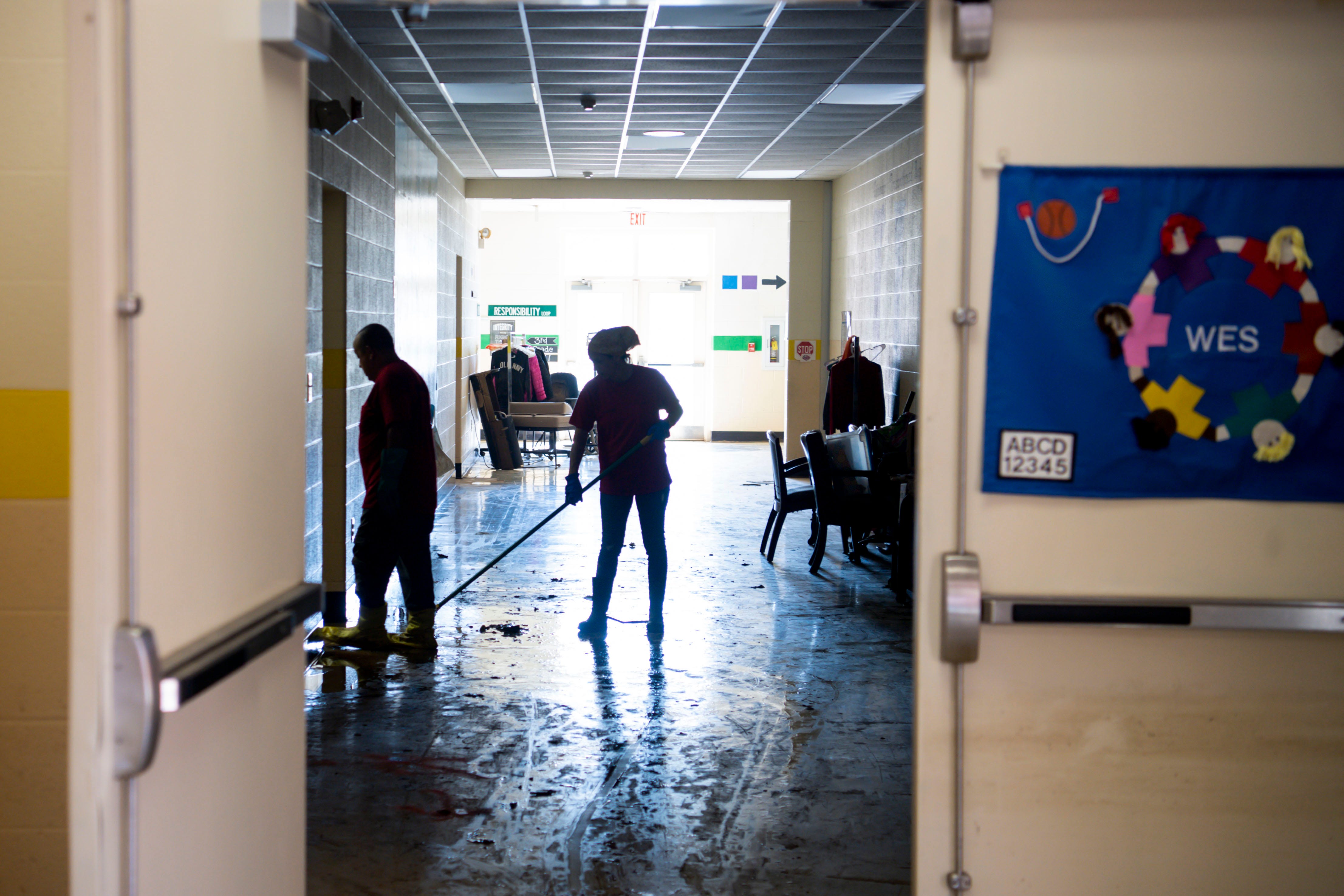 Clean up crew members are silhouetted in Waverly Elementary School Principal as they work on Wednesday, Aug. 25, 2021, after flash flooding swept through the town of Waverly, Tenn.