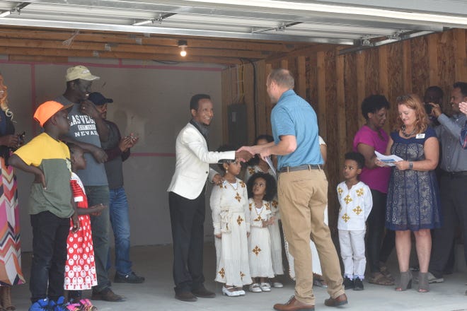 Mike Nold, a lending officer at Wells Fargo and volunteer chapter chair with Habitat for Humanity, shakes Henok Teklezgi's hand.