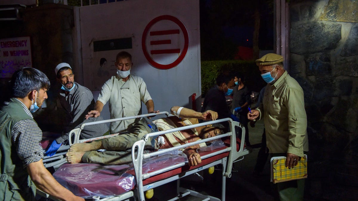 Medical and hospital staff bring an injured man on a stretcher for treatment after two powerful explosions, which killed at least six people, outside the airport in Kabul on August 26, 2021.