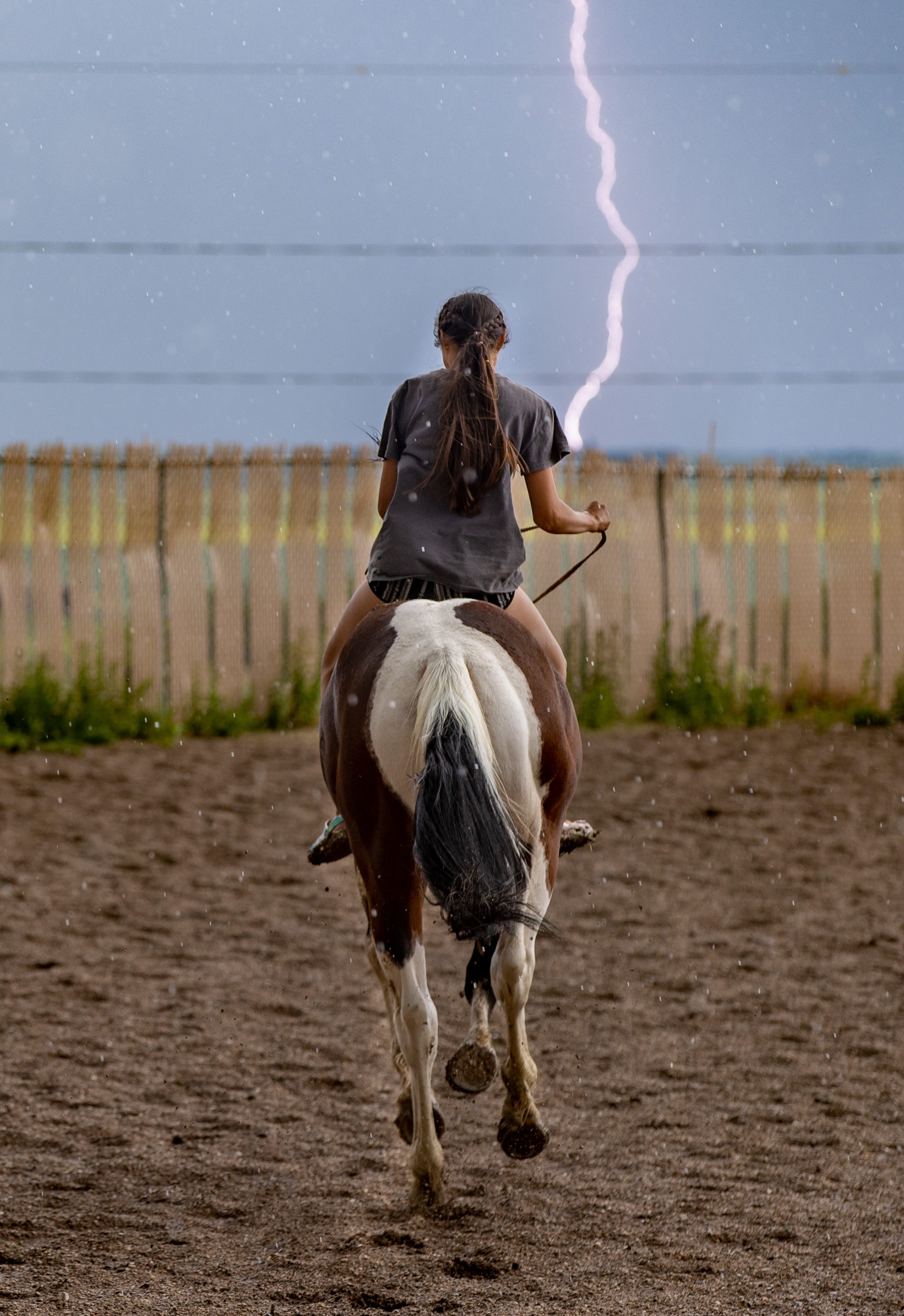 Lightning strikes as a young rider takes off on a horse at the Parshall Lucky-Mound Rodeo as a storm rolls in across the plains. June 26, 2021