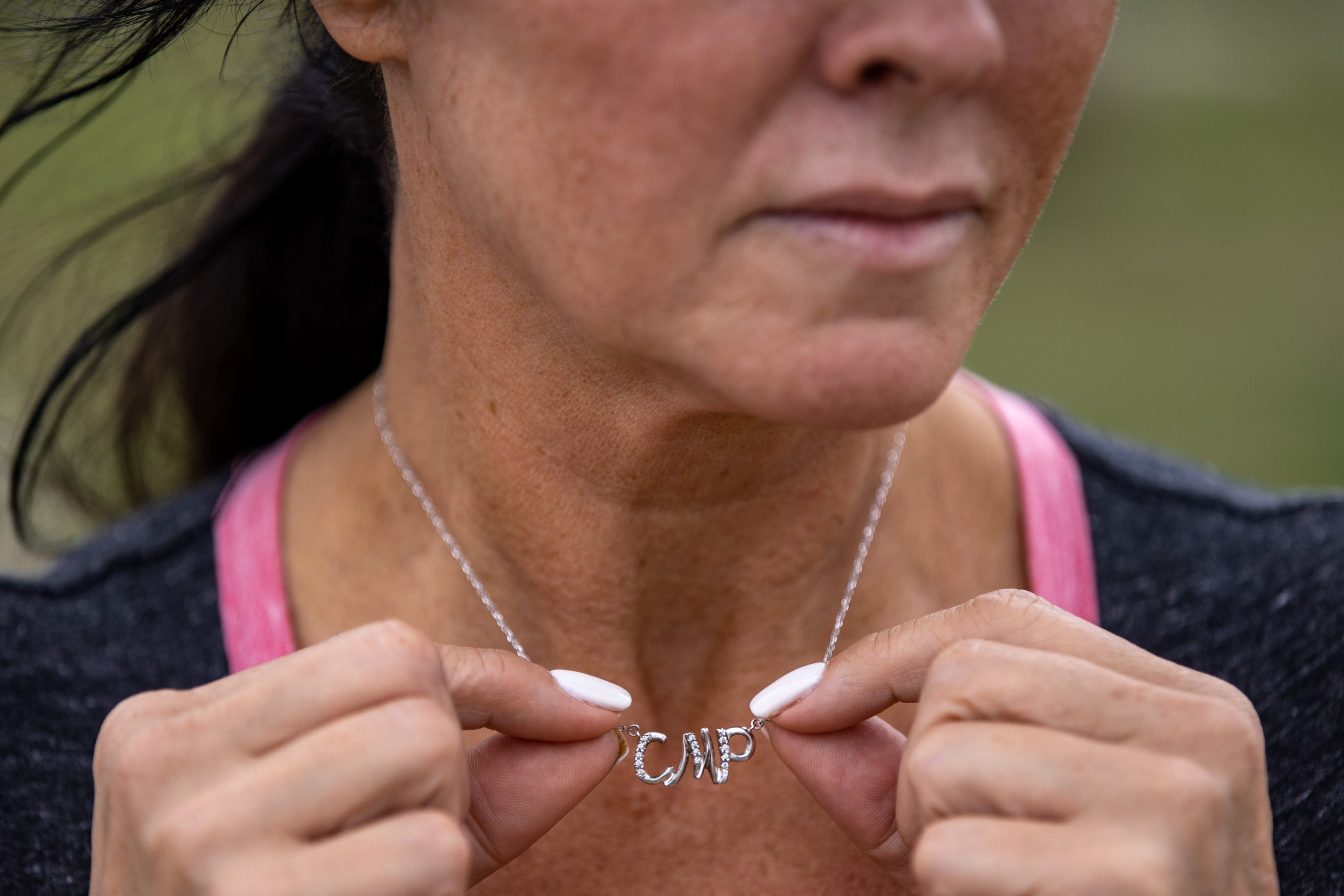 Rhonda Packineau wears a necklace with her daughter, Cheyenne Packineau's, initials as she visits her grave in the Parshall, North Dakota Meadows Cemetery. Cheyenne, a standout basketball player at Parshall High School who holds the all-time scoring record, began taking pain pills in high school to cope with a sports injury. Her abuse continued into college, where she got a full-ride scholarship for basketball. In 2018, she was found dead from an overdose of Fentanyl in a Bismarck hotel room at just 21 years old. Today, Cheyenne's family raises Cheyenne's son, Kasten, as they aim to raise awareness about addiction in their daughter's memory. June 26, 2021