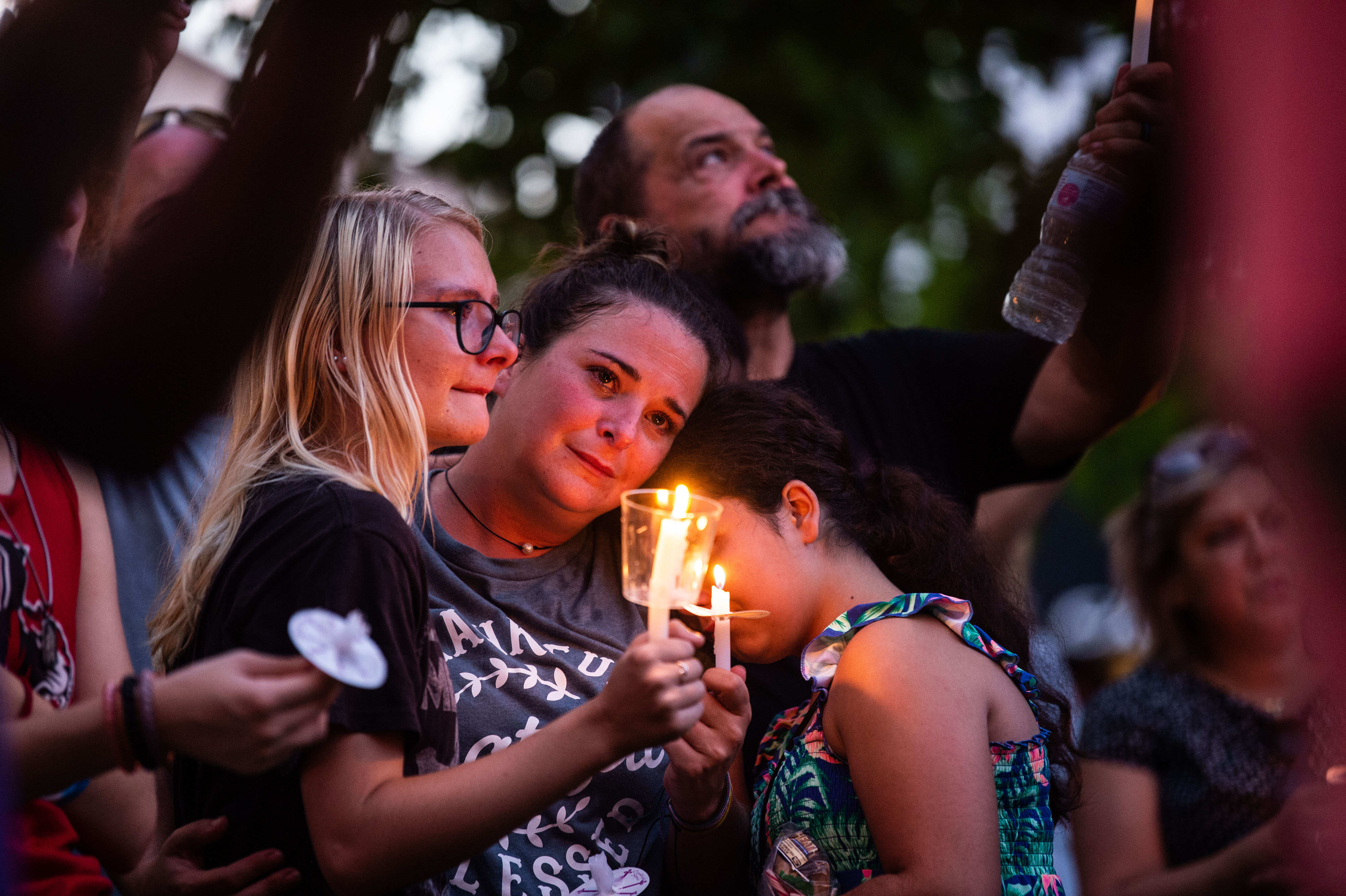 Kelli Lutts, holds her daughters, Chloe (right) and Henslee (left), 10,  as community members gather for a vigil in Waverly, Tenn., Friday, Aug. 27, 2021. The vigil honored the 20 people who died during the catastrophic flood that hit the town the previous weekend.